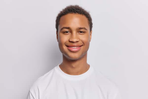 Portrait of pleased dark skinned man with short curly hair