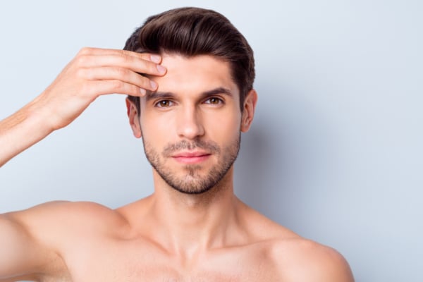 Portrait of a young man touching forehead